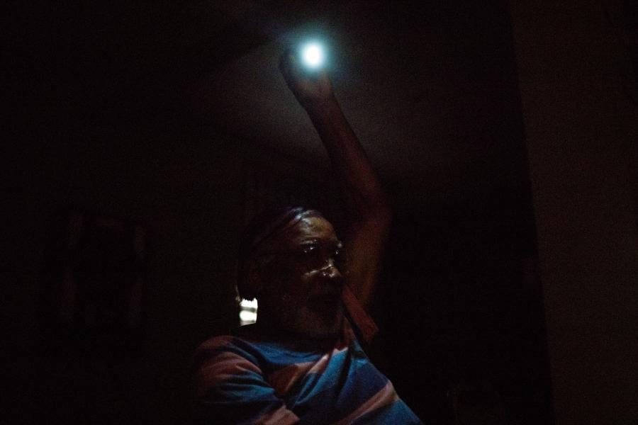 person hanging a lightbulb in a dark room