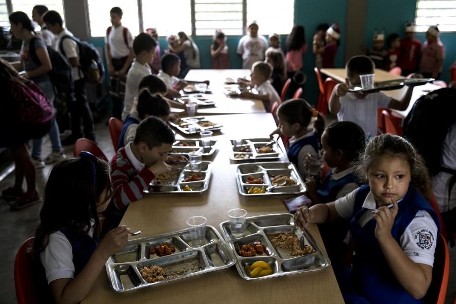 Students at the Jose R. Barreras school eat lunch in a dark cafeteria 