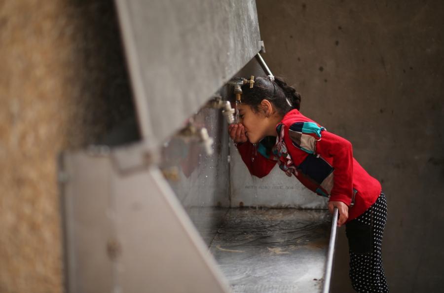 A Palestinian girl drinks water from a public tap in Jabaliya refugee camp in the northern Gaza, Jan. 24, 2017. 