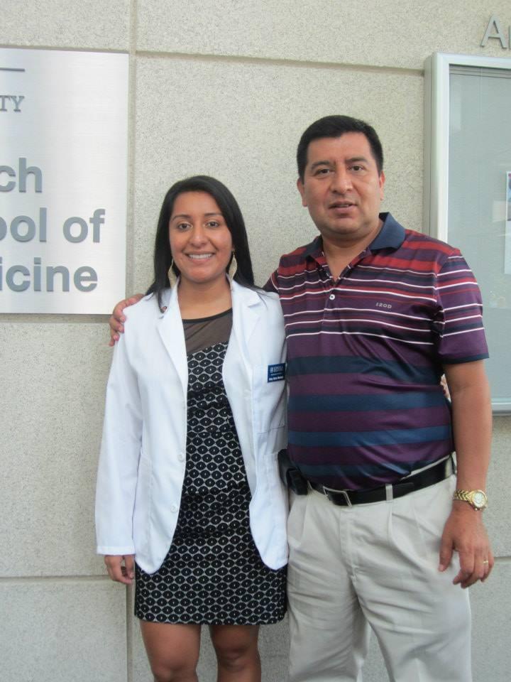 Woman in white coat smiling, posing with older man