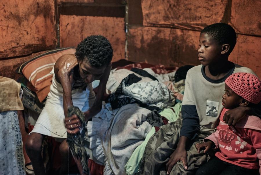 Lutango Nompumelelo, 42, washes before going to the hospital. She shared her bed with her children Mcepisi and Akhona. 2013, Gugulethu, Cape Town.