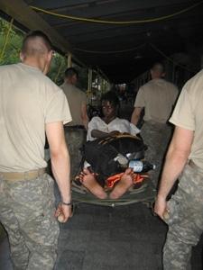 Paratroopers from the 82nd Airborne carry Nathalie LeBrun to a military ambulance.