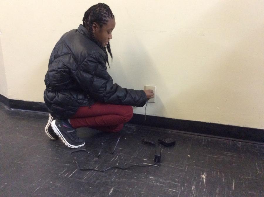 Arany plugs her mother's ankle bracelet into the wall.