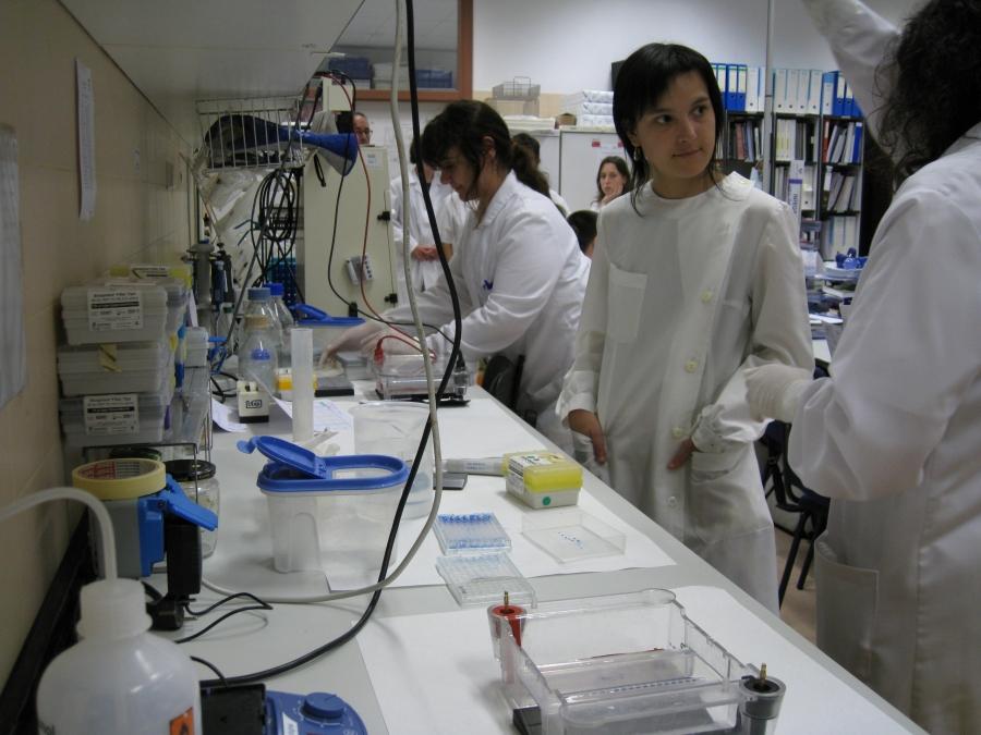 Workers in white suit at lab table with instruments