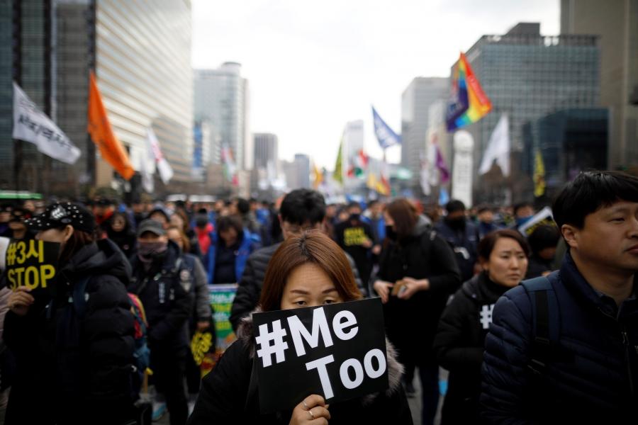 a woman holds a #MeToo sign  in front of her face