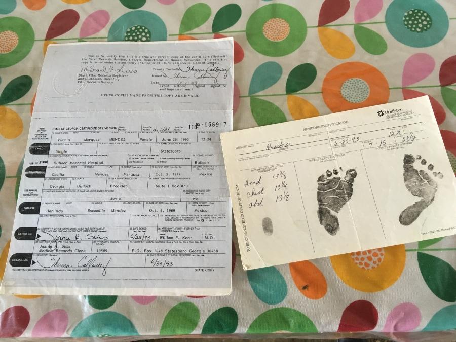 Birth certificate, with text and inked footprints of baby, sitting on flower-print sheets