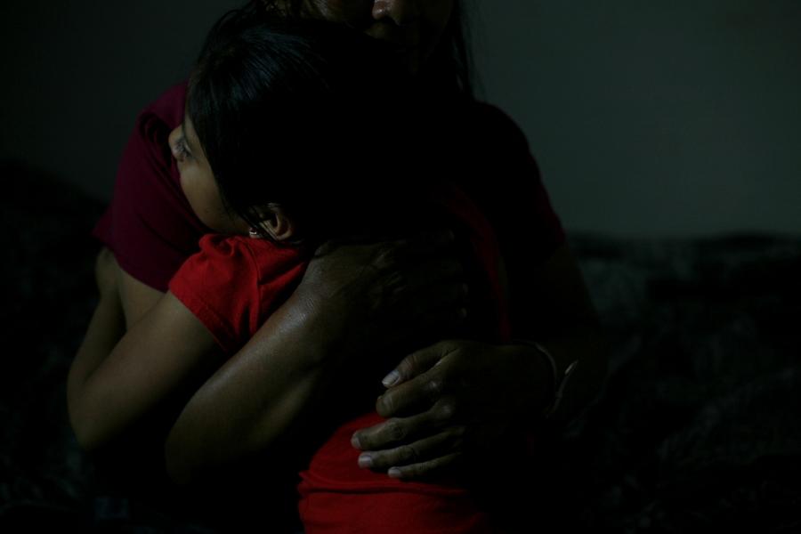 Woman embracing young girl, faces not shown