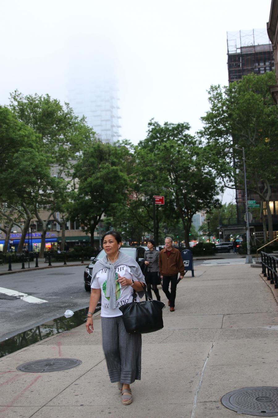 Woman walking on city sidewalk holding purse