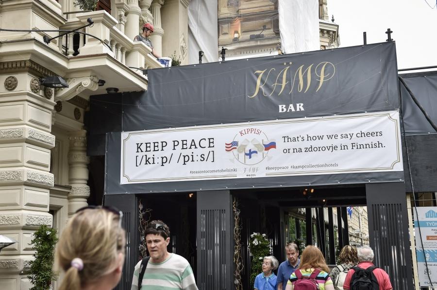 A sign at a bar reads: "Keep peace. That's how we say cheers ... in Finnish." The sign also shows a Russian flag and a US flag.