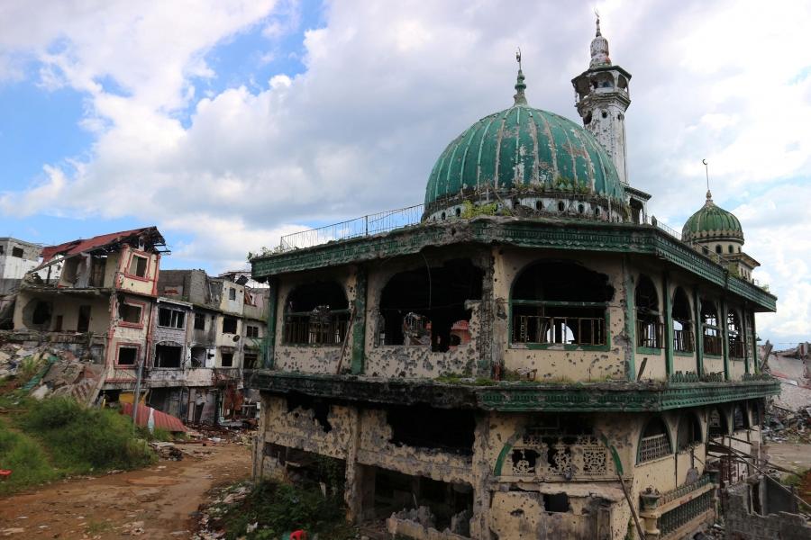 The dome of a damaged mosque rises among rubble in a city