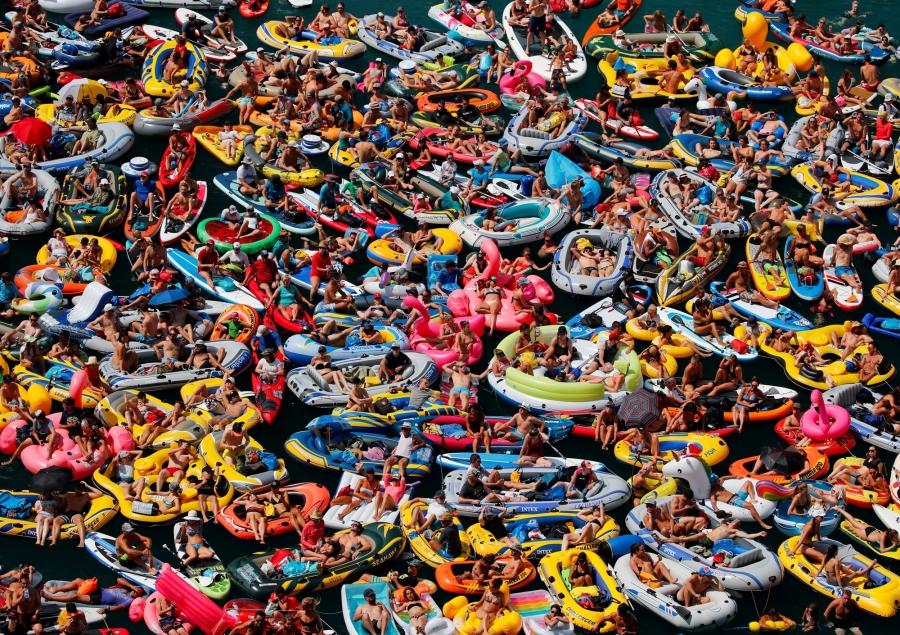 People on inflatable boats enjoy the sun as they watch the Red Bull Cliff Diving competition on Lake Lucerne in Sisikon, Switzerland.