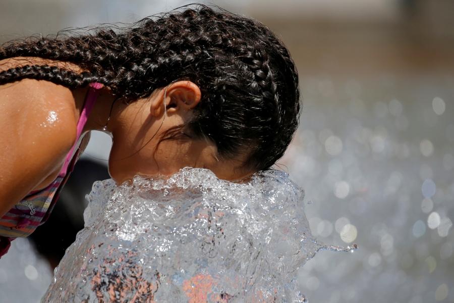A child cools off in a fountain as a summer heat wave with high temperatures continues in Paris.