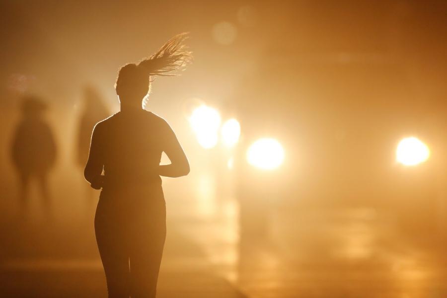 A women jogs along a roadside as temperatures cool off after sunset in Oceanside, California.
