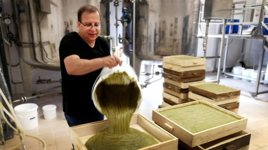 A man in a factory pours a thick green substance into a square mold