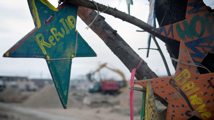 A wooden memorial star is seen hanging from a tree as heavy machinery excavate land in Breezy Point in Queens, New York, six months after the landfall of Superstorm Sandy in April 2013.
