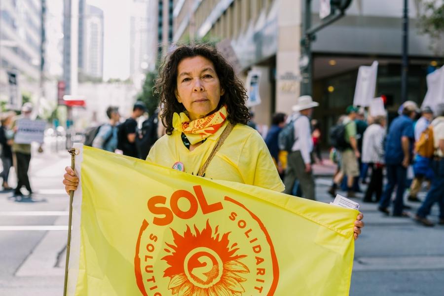 Alicia Rivera is shown holding a yellow flag during a demonstration in San Francisco, California.