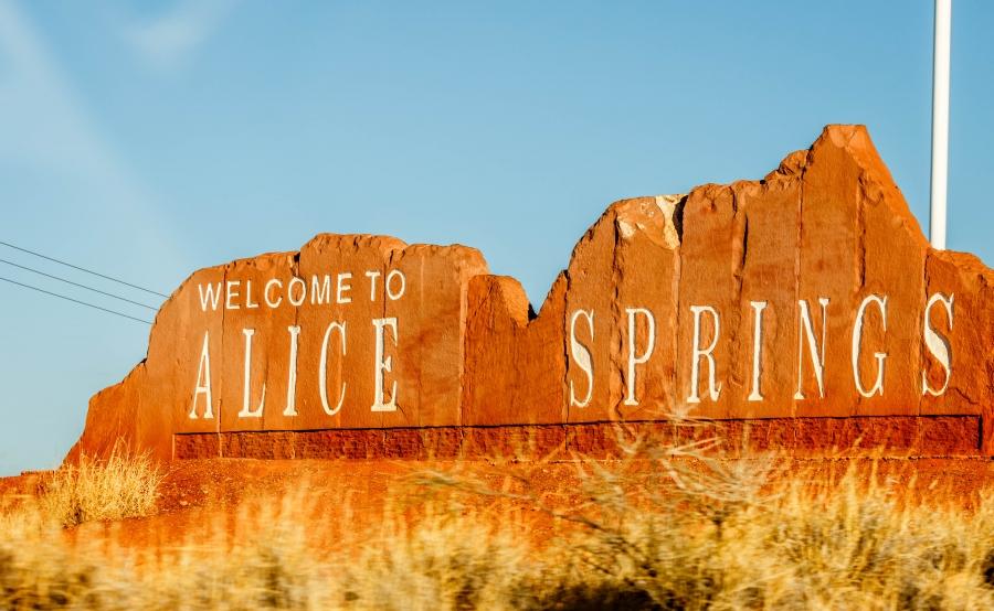 A stone sign for Alice Springs is shown in the shape of the mountain skyline.