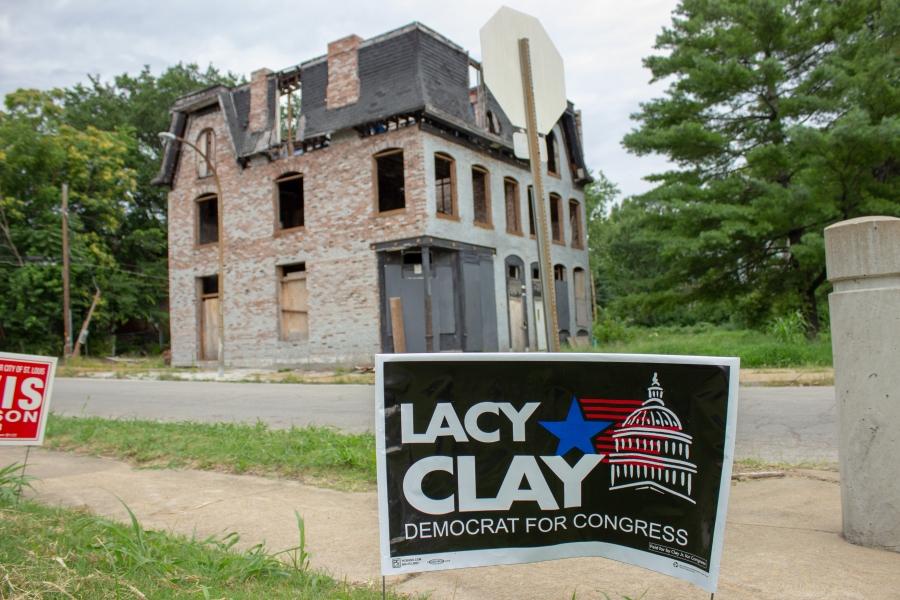 a lacy clay yard sign in front of an abandoned house in st louis