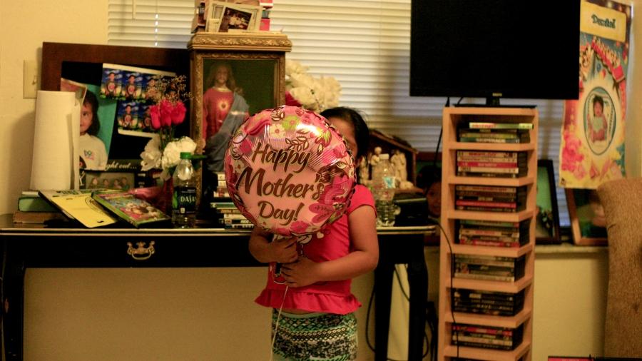 Girl in room with Mother's Day balloon in front of her face