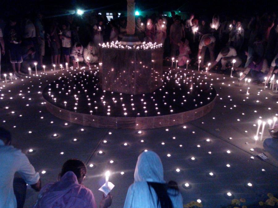 People sit around light candles, with scarves covering their heads