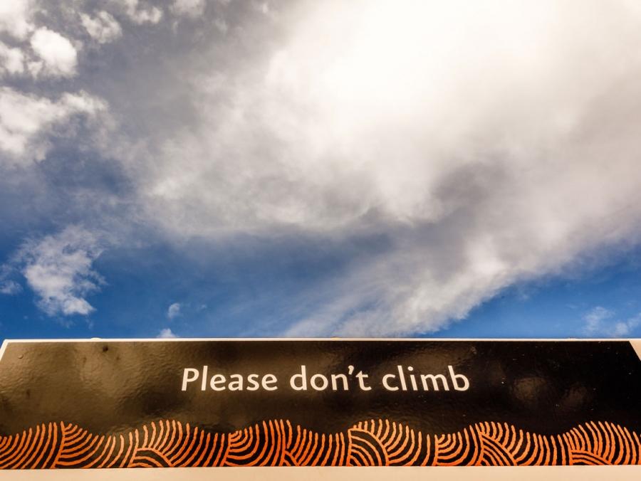 Signage at the base of Uluru reads, 'please don't climb.'
