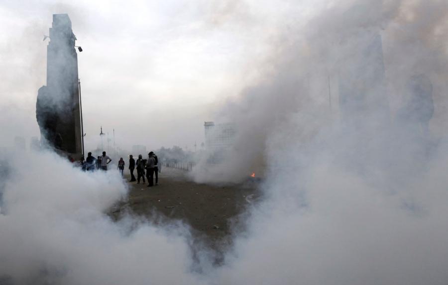 People stand surrounded by clouds of tear gas