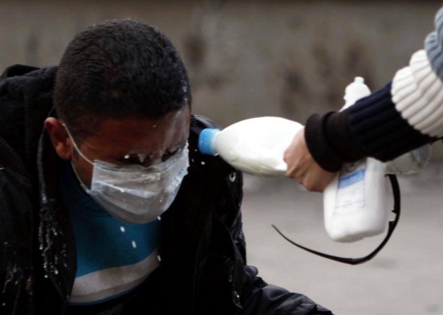 A man has milk splashed into his eyes to wash out tear gas.