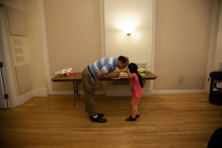 man bending over to meet forehead of young child in hallway
