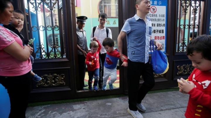 A male couple leaves a kindergarten with their sons. 