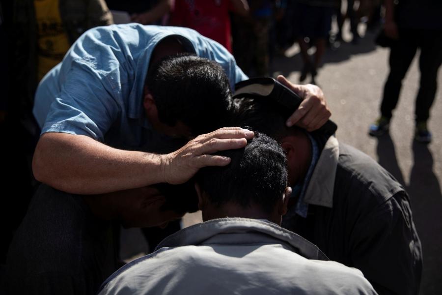 Pastor Jose Murcia is shown with his hands on two people's heads preaching.