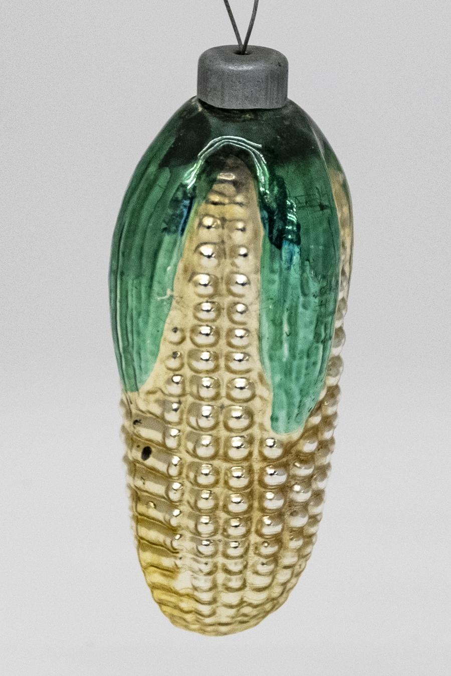 A golden tin corn-shaped ornament with green-painted leaves. 