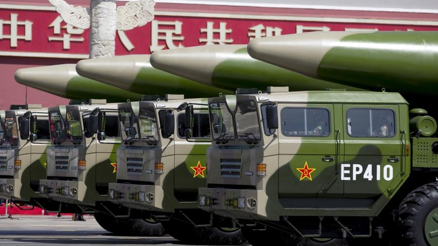 Green-colored military vehicles carry DF-26 ballistic missiles. 