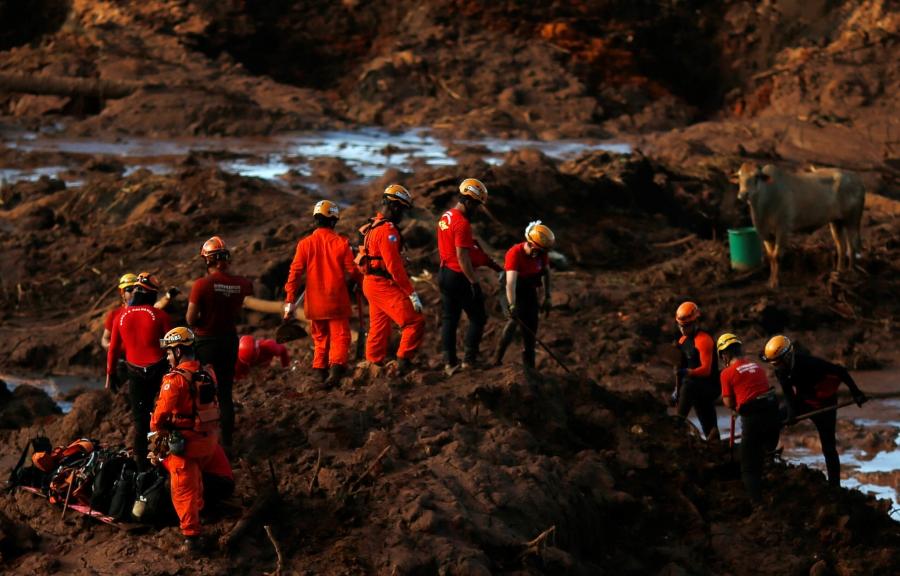 Members of a rescue team search for victims in a sea of red mud 
