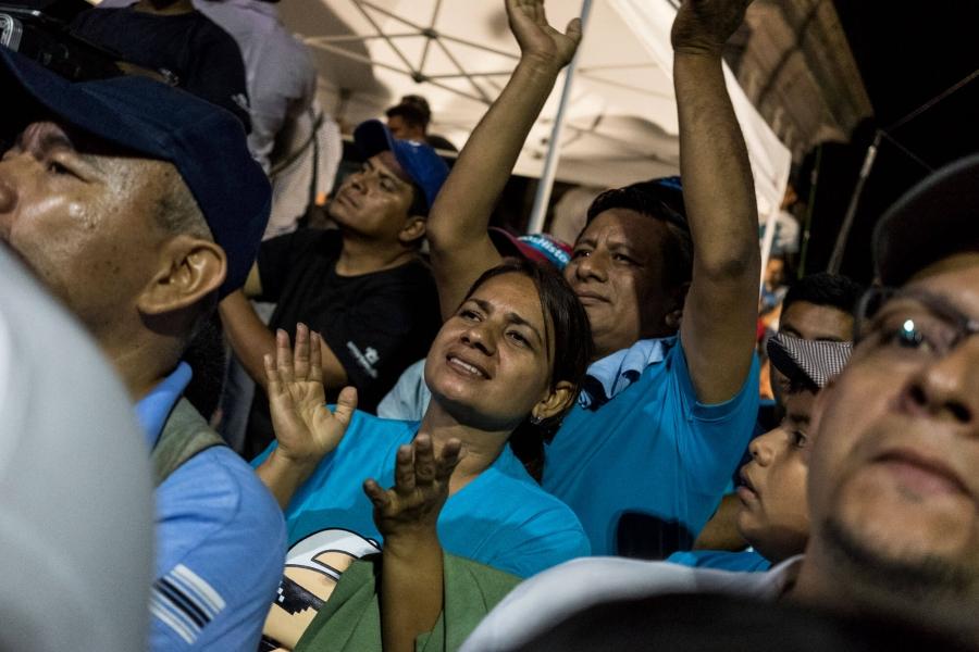Young Salvadoran woman in blue shirt at a rally. 