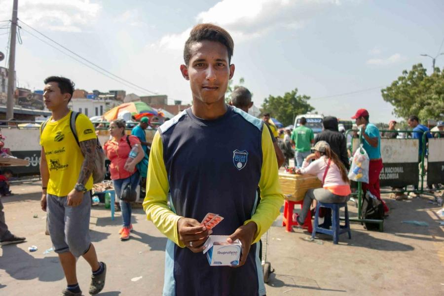 A young man wearing a sports jersey sells medicine tablets on the street. 