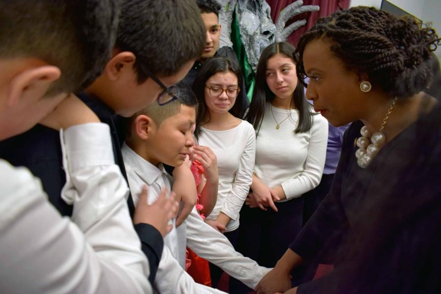 Ayanna Pressley holds the hands of a young boy who is visibly upset.