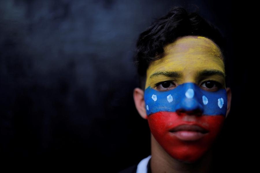 a closeup of a young boy with the Venezuelan flag painted on his face 