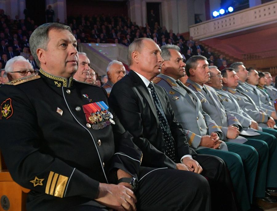 Russia's President Putin sits next to several military members 