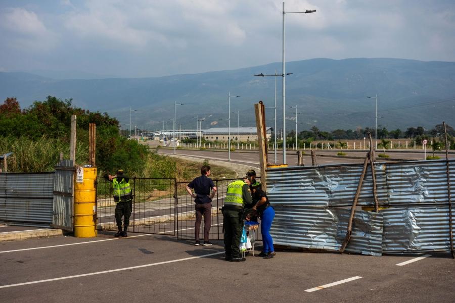 Police stand near a barricaded bridge. 