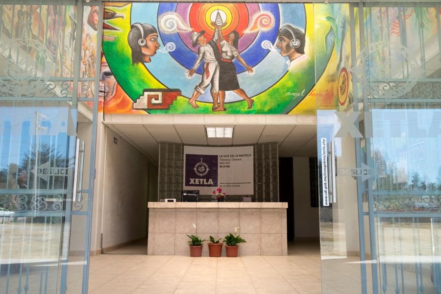 The lobby at XETLA is shown with a desk center frame under a colorful mural.