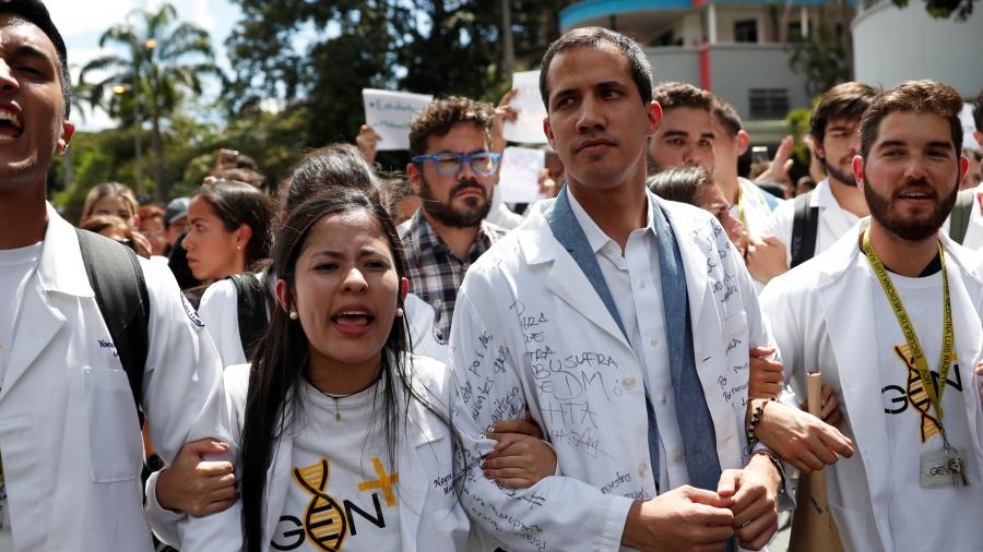 Protesters walk in white with interim President Juan Guaidó. 