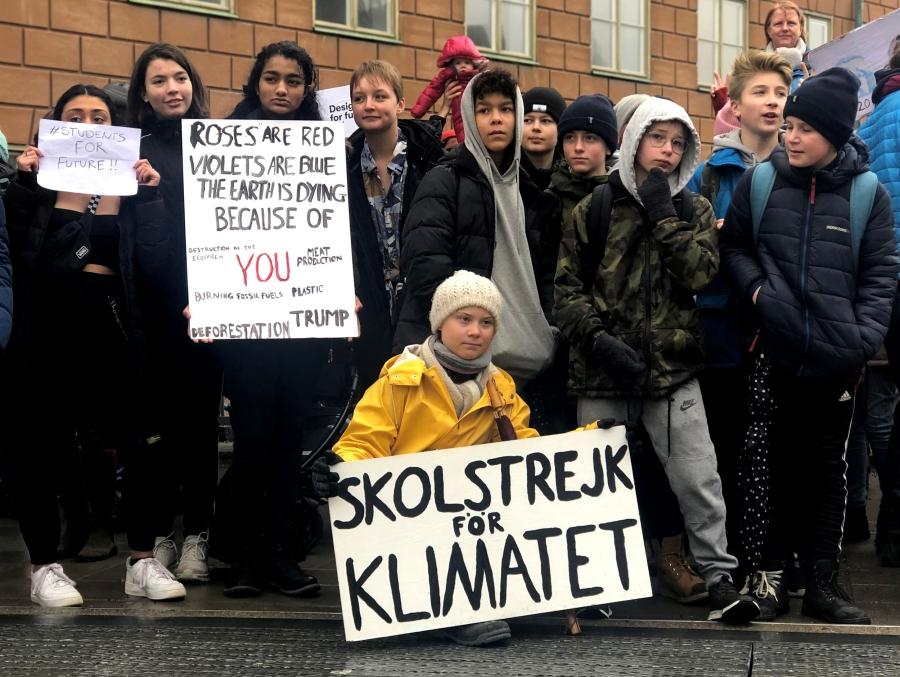 A group of children pose with signs about climate change