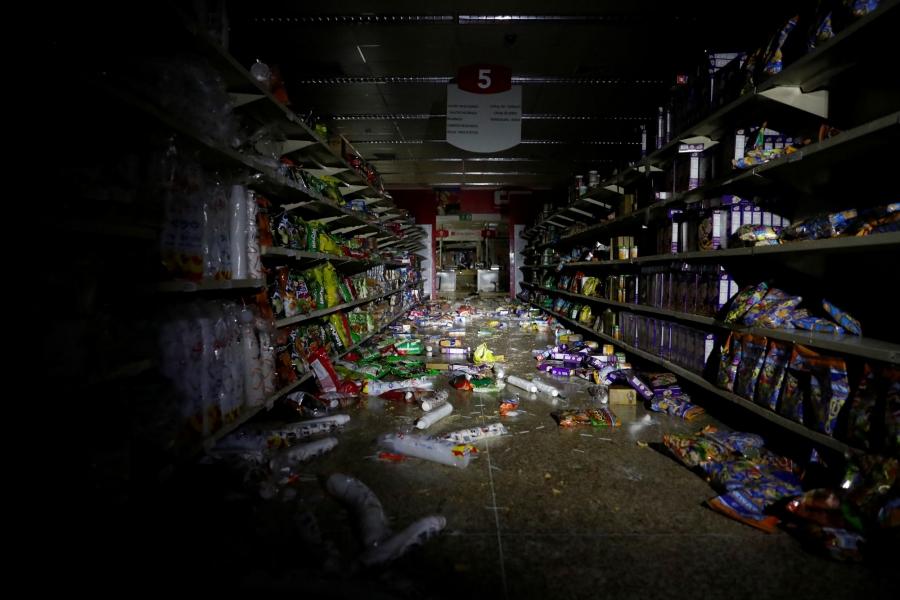 The shelves of a market are shown with items thrown all over the floor after it was looted. 