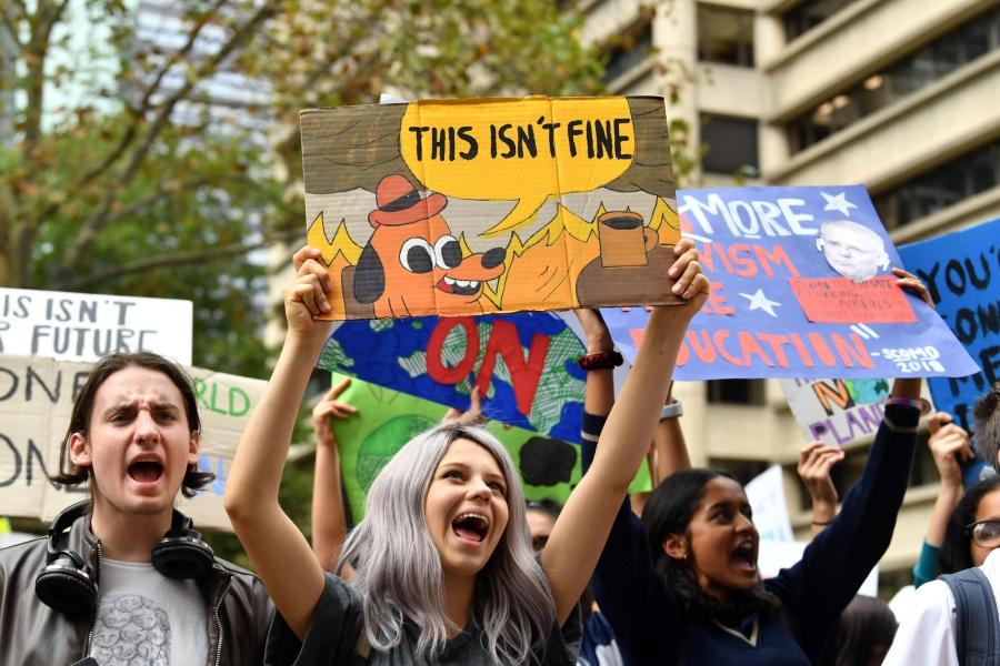 Students in Australia are shown with a sign that reads, "This isn't fine."