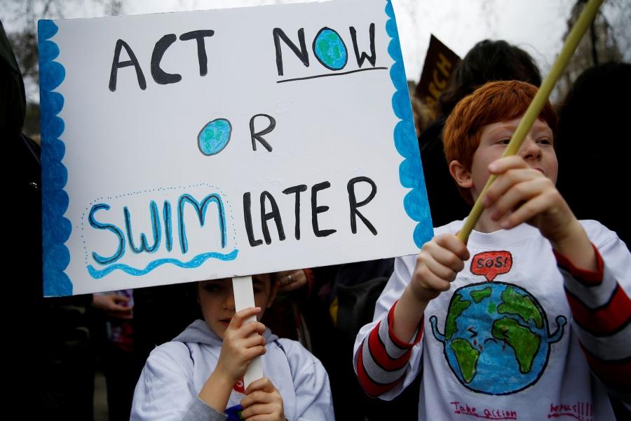 Two children are shown protesting against climate change with a sign that reads: "Act now or swim later."