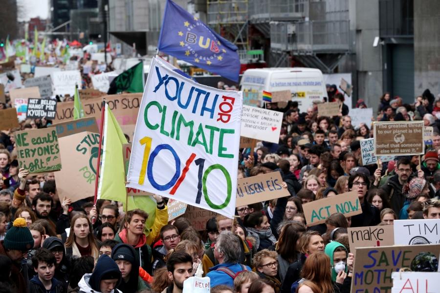 Thousands of demonstrators are shown in the streets of Belgium with one carrying a sign that reads: "Youth for climate 10/10."