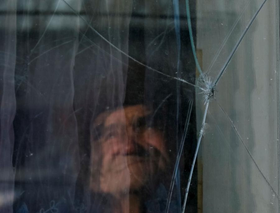 A person is shown blurry behind a pane of glass that has a hole in it.