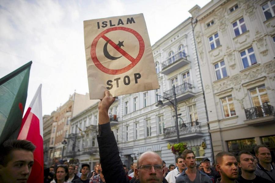 a white man holds up a sign that reads "stop islam"