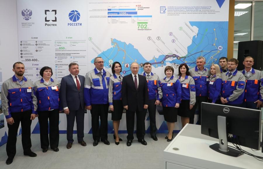 Russian President Vladimir Putin poses with workers