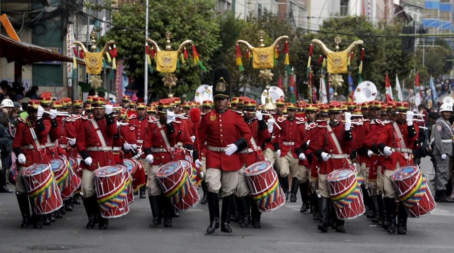 a string of men in red uniforms march with drums 